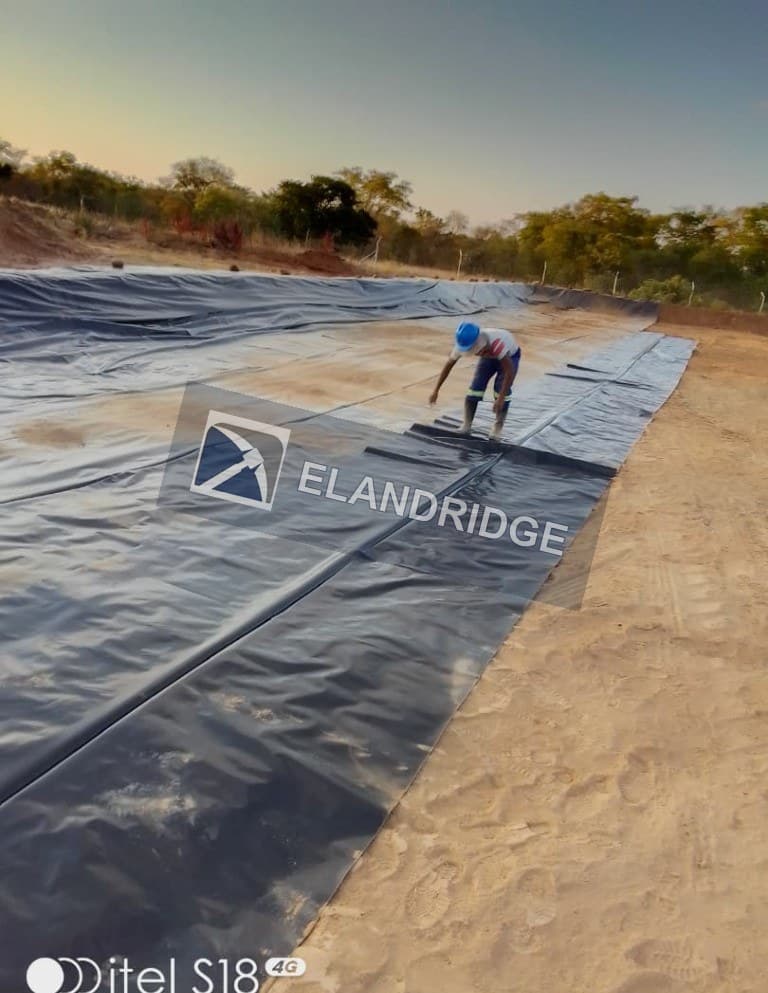 Laying geomembrane on a process pond at Kambuzi